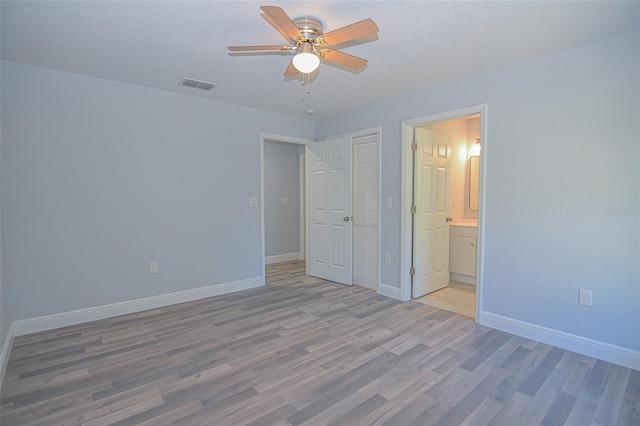 unfurnished bedroom with visible vents, ensuite bath, light wood-style flooring, and baseboards