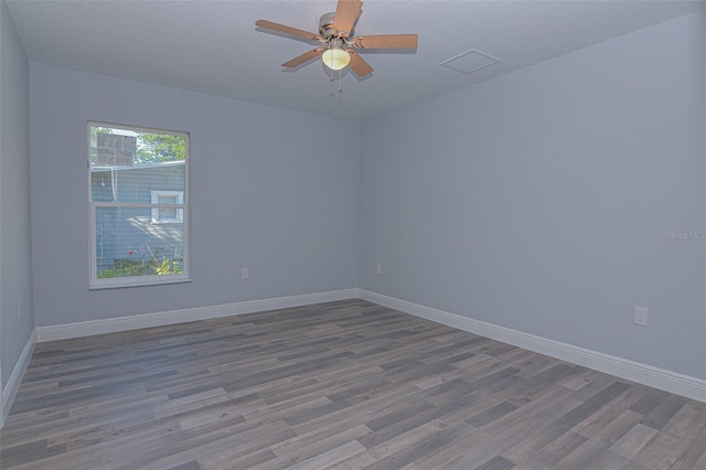 spare room featuring visible vents, ceiling fan, baseboards, and wood finished floors