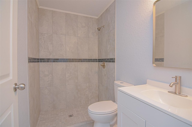 full bathroom with a textured wall, toilet, vanity, tiled shower, and crown molding