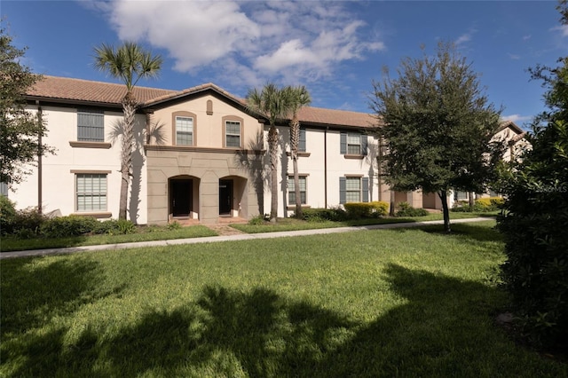 view of front of property featuring a tiled roof, a front yard, and stucco siding