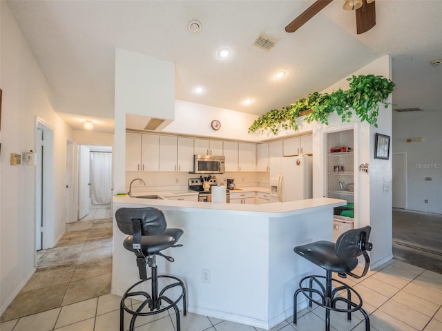 kitchen with a peninsula, a breakfast bar, a sink, visible vents, and appliances with stainless steel finishes