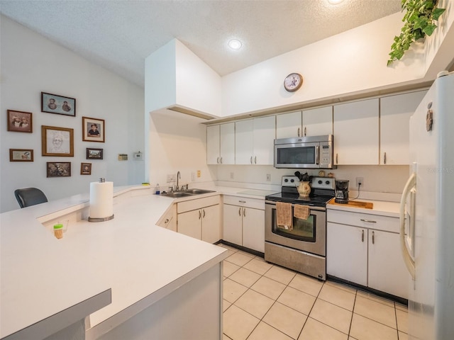 kitchen with light tile patterned floors, appliances with stainless steel finishes, a peninsula, light countertops, and a sink