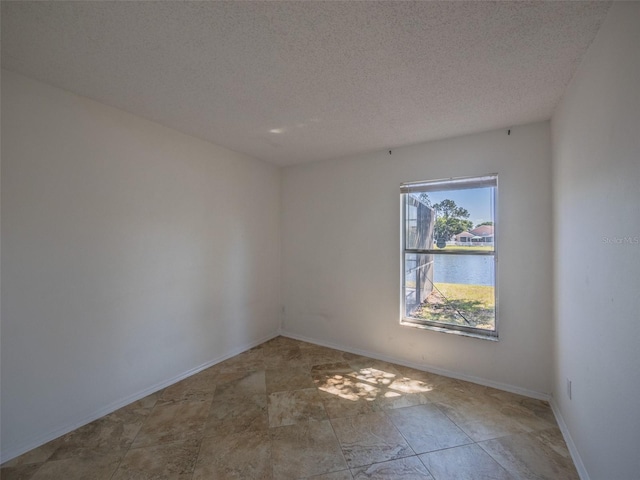 empty room featuring a textured ceiling and baseboards