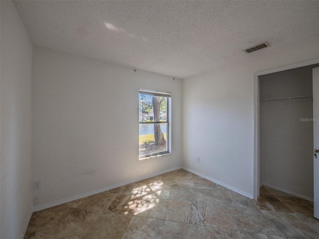 unfurnished bedroom with a closet, visible vents, a textured ceiling, and baseboards