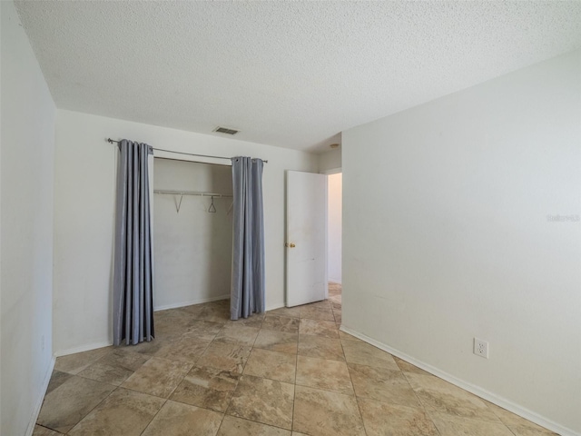 unfurnished bedroom with a textured ceiling, a closet, visible vents, and baseboards