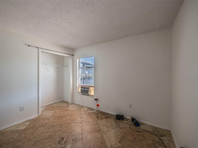 unfurnished bedroom featuring a textured ceiling, a closet, cooling unit, and baseboards