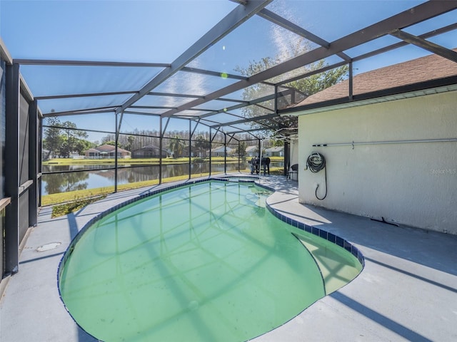 pool featuring glass enclosure, a patio area, and a water view