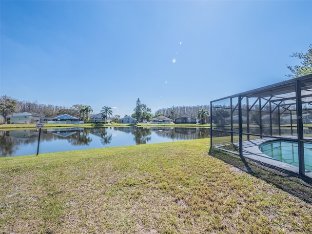 view of yard with glass enclosure, a water view, and an outdoor pool