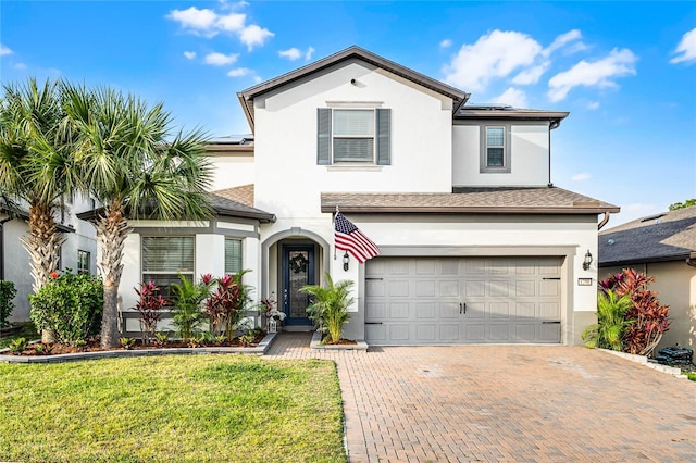 traditional-style home with decorative driveway, solar panels, stucco siding, a garage, and a front lawn