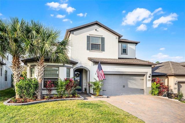 traditional-style home with a front lawn, decorative driveway, an attached garage, and stucco siding