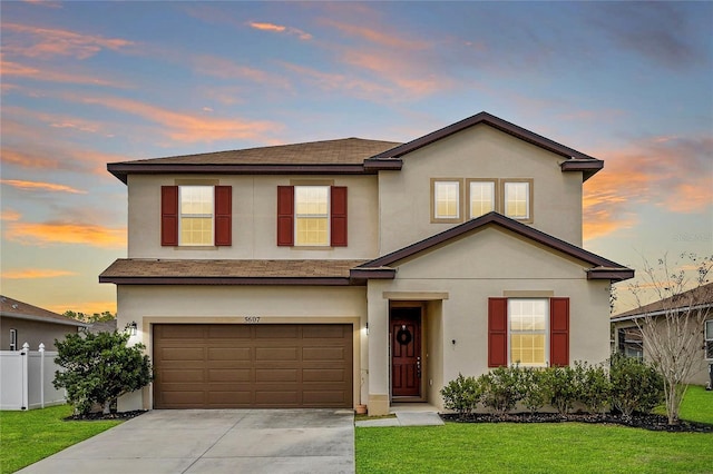 traditional-style house featuring stucco siding, an attached garage, fence, driveway, and a front lawn