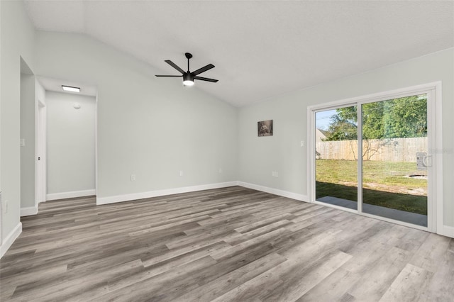 spare room with vaulted ceiling, wood finished floors, a ceiling fan, and baseboards