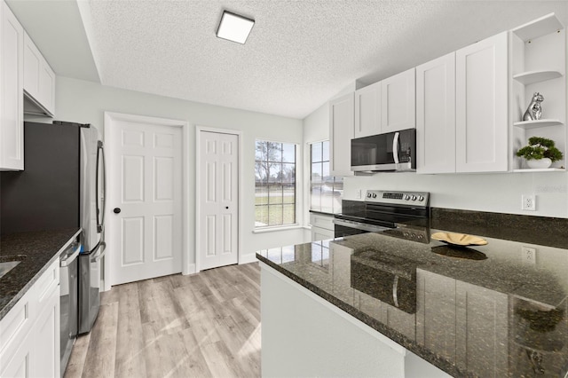 kitchen featuring white cabinets, dark stone countertops, stainless steel appliances, light wood-style floors, and open shelves