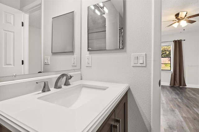 bathroom featuring baseboards, a textured wall, ceiling fan, wood finished floors, and vanity