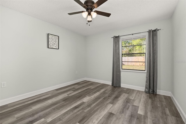 empty room featuring dark wood-style floors, ceiling fan, a textured ceiling, and baseboards