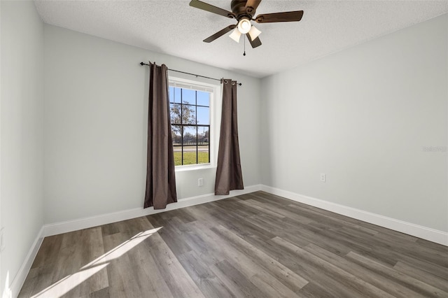 empty room with a ceiling fan, dark wood-style flooring, a textured ceiling, and baseboards