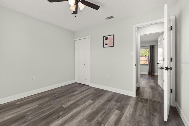 unfurnished bedroom featuring a closet, dark wood-style flooring, visible vents, and baseboards