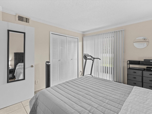 bedroom featuring a textured ceiling, tile patterned flooring, visible vents, a closet, and crown molding