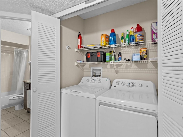 clothes washing area with a textured ceiling, laundry area, light tile patterned floors, and washer and clothes dryer