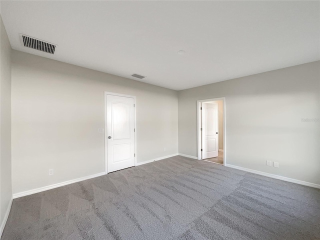 spare room with carpet, visible vents, and baseboards