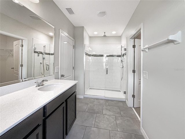 full bath featuring a stall shower, vanity, baseboards, and a spacious closet