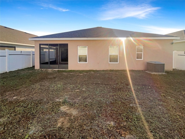 back of property featuring cooling unit, a fenced backyard, a sunroom, and stucco siding