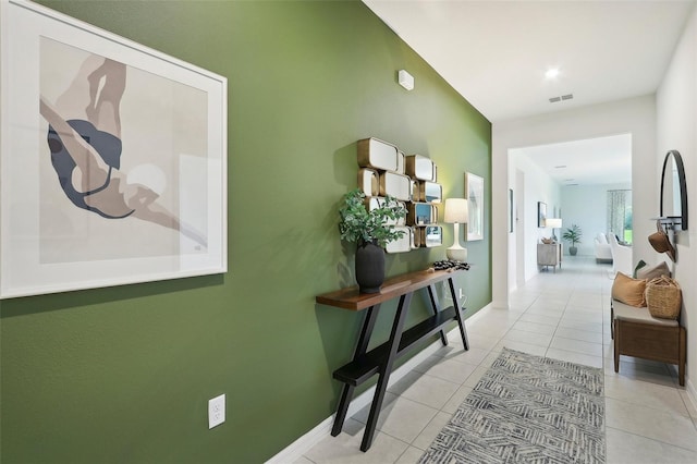 corridor featuring light tile patterned floors, visible vents, and baseboards