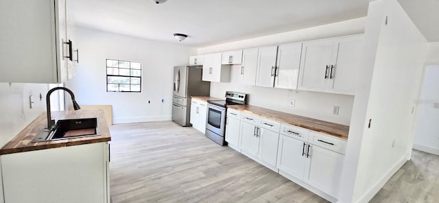 kitchen featuring stainless steel appliances, light wood-style floors, white cabinets, and a sink