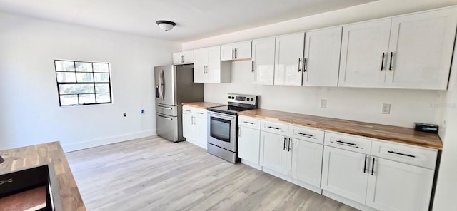 kitchen featuring baseboards, light wood-style flooring, appliances with stainless steel finishes, white cabinetry, and wooden counters