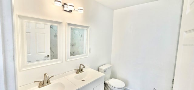 bathroom featuring double vanity, a sink, and toilet