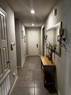 hall featuring baseboards and dark tile patterned floors