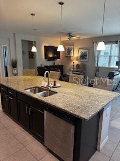 kitchen featuring a kitchen island with sink, light stone countertops, pendant lighting, and a sink