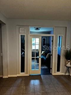 doorway with tile patterned floors and baseboards