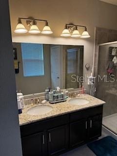 bathroom featuring a sink, double vanity, and a shower stall