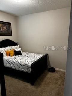 carpeted bedroom featuring baseboards and a textured ceiling