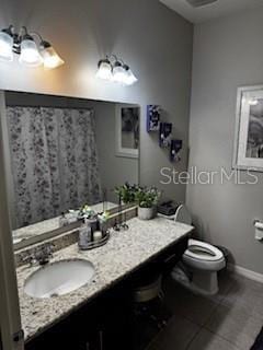 bathroom with baseboards, toilet, and vanity