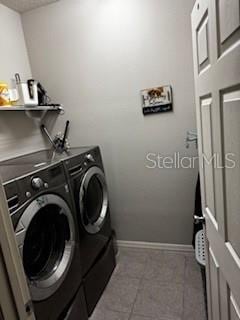 laundry room featuring baseboards, separate washer and dryer, laundry area, and tile patterned flooring