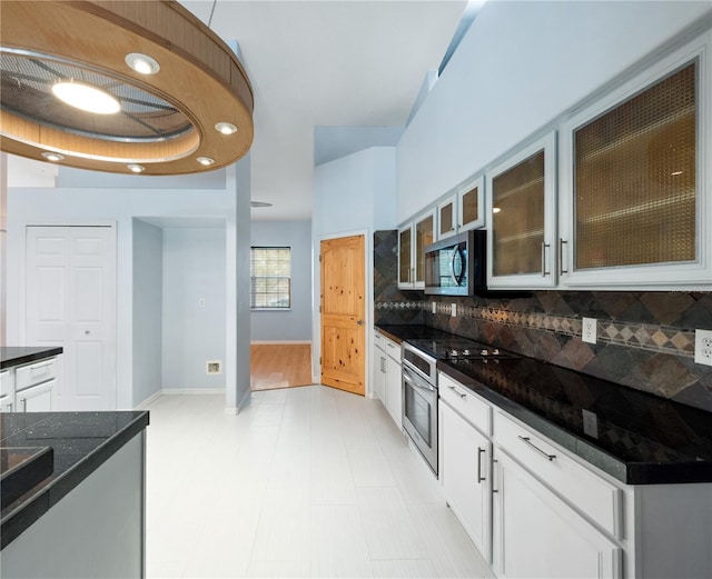 kitchen featuring appliances with stainless steel finishes, white cabinetry, glass insert cabinets, and backsplash