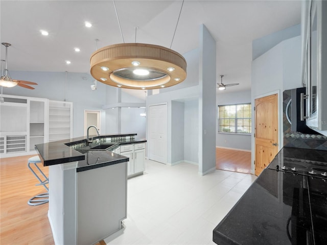 kitchen with a ceiling fan, open floor plan, a sink, and high vaulted ceiling