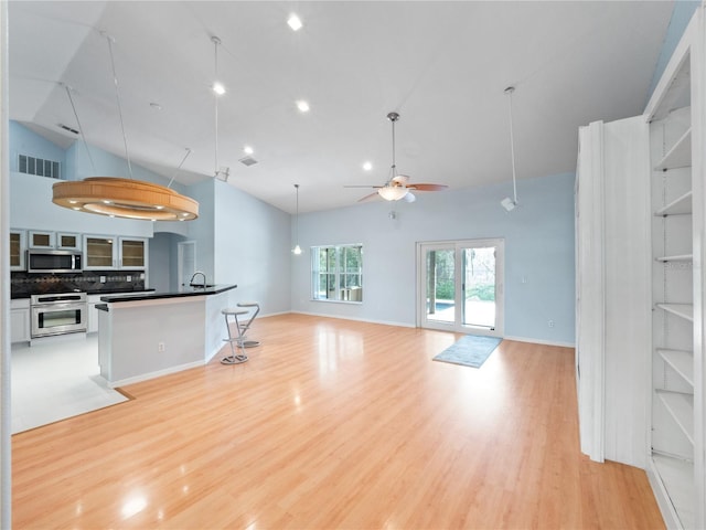 living area featuring ceiling fan, high vaulted ceiling, light wood finished floors, and visible vents