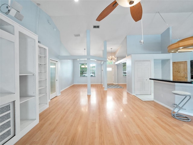 unfurnished living room with visible vents, baseboards, wood finished floors, a high ceiling, and ceiling fan with notable chandelier