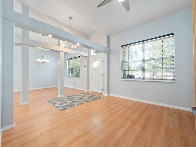 foyer with ceiling fan with notable chandelier, wood finished floors, and baseboards