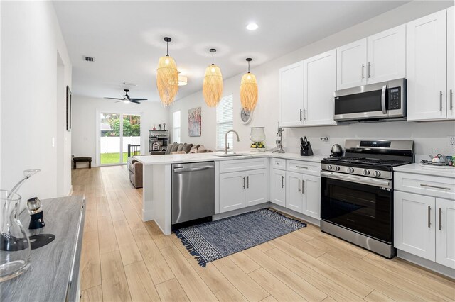 kitchen with a sink, stainless steel appliances, open floor plan, a peninsula, and visible vents