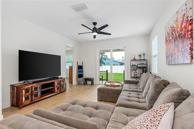 living room featuring a ceiling fan, visible vents, and light wood finished floors