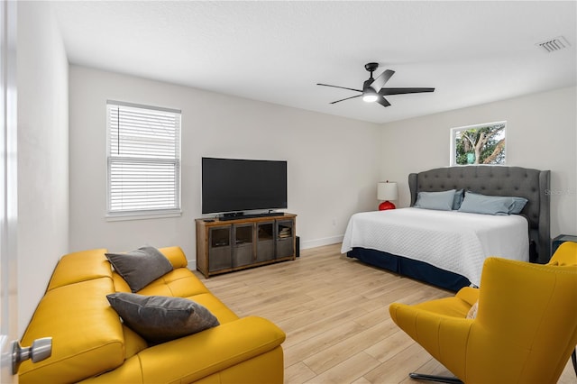 bedroom with visible vents, a ceiling fan, light wood finished floors, and baseboards