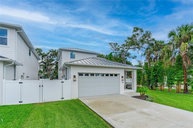 view of front of property featuring a front lawn, a garage, a gate, a standing seam roof, and driveway