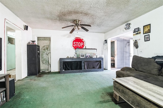 living room featuring carpet, a ceiling fan, and a textured ceiling