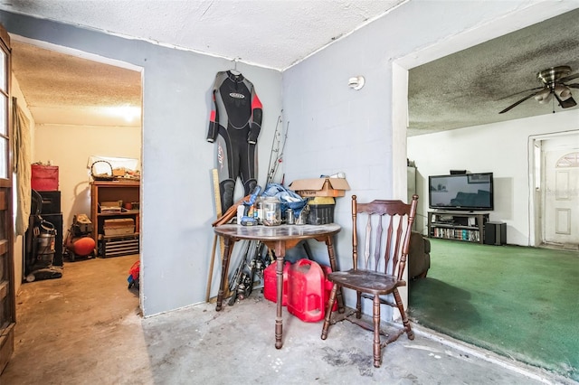 miscellaneous room with a textured ceiling, ceiling fan, concrete floors, and concrete block wall