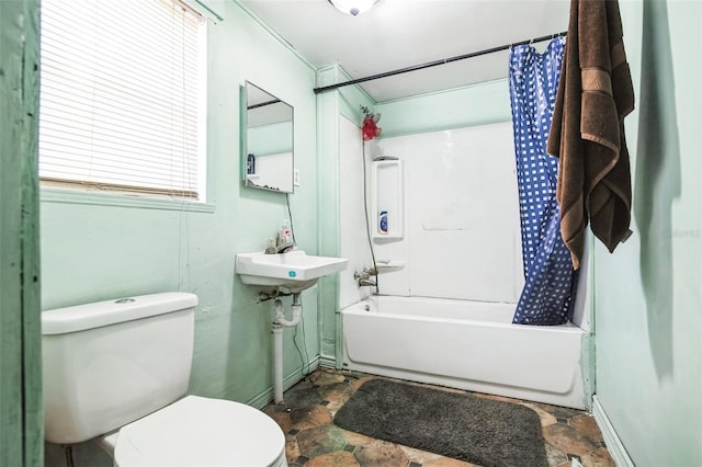 full bathroom with toilet, shower / tub combo, stone finish floor, a sink, and baseboards