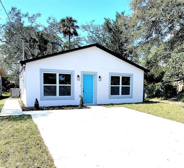 bungalow-style house featuring central AC unit, a front yard, and stucco siding